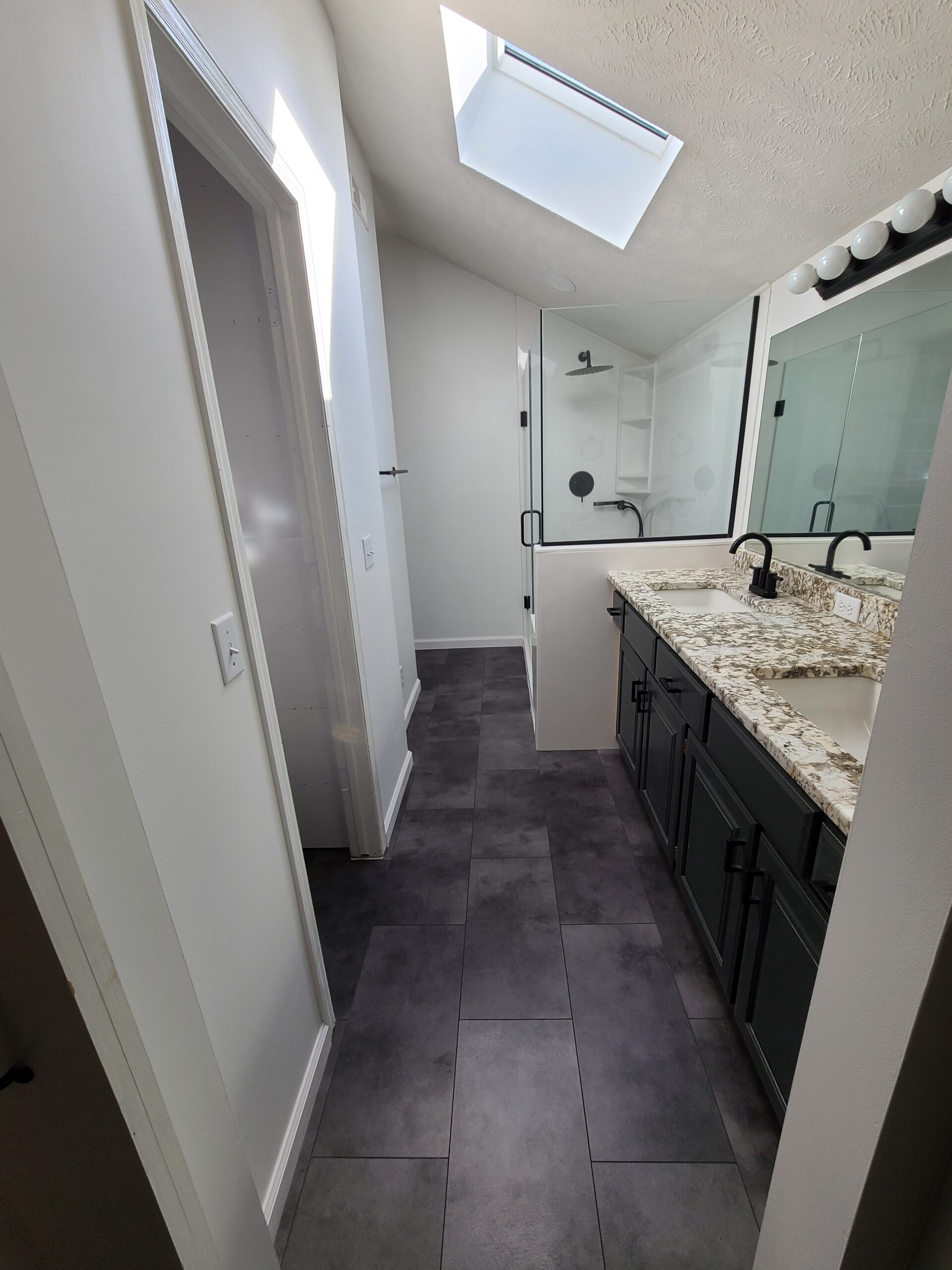 A bathroom remodel is completed by Houston Remodel Service. it includes a shower, two sinks, and even a skylight.