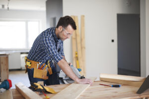 A general contractor cuts a piece of board with his saw as he does home remodeling.
