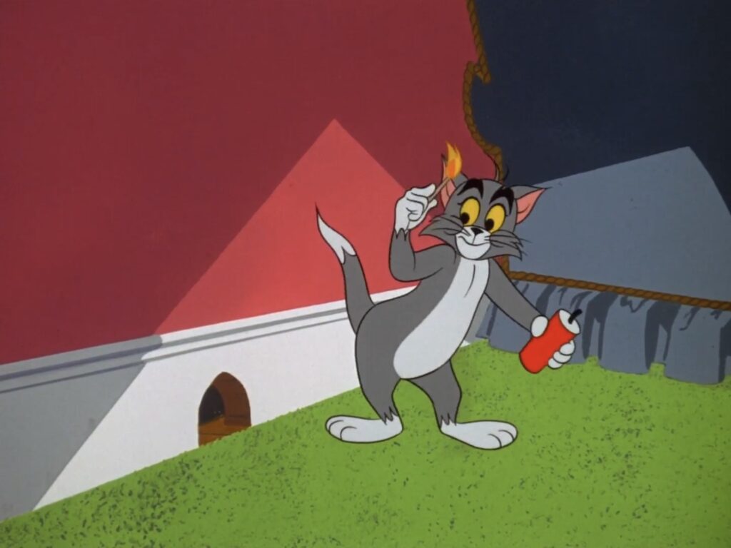 Tom the cat stands in the hallway outside of Jerry's hole. He is lighting dynamite.
